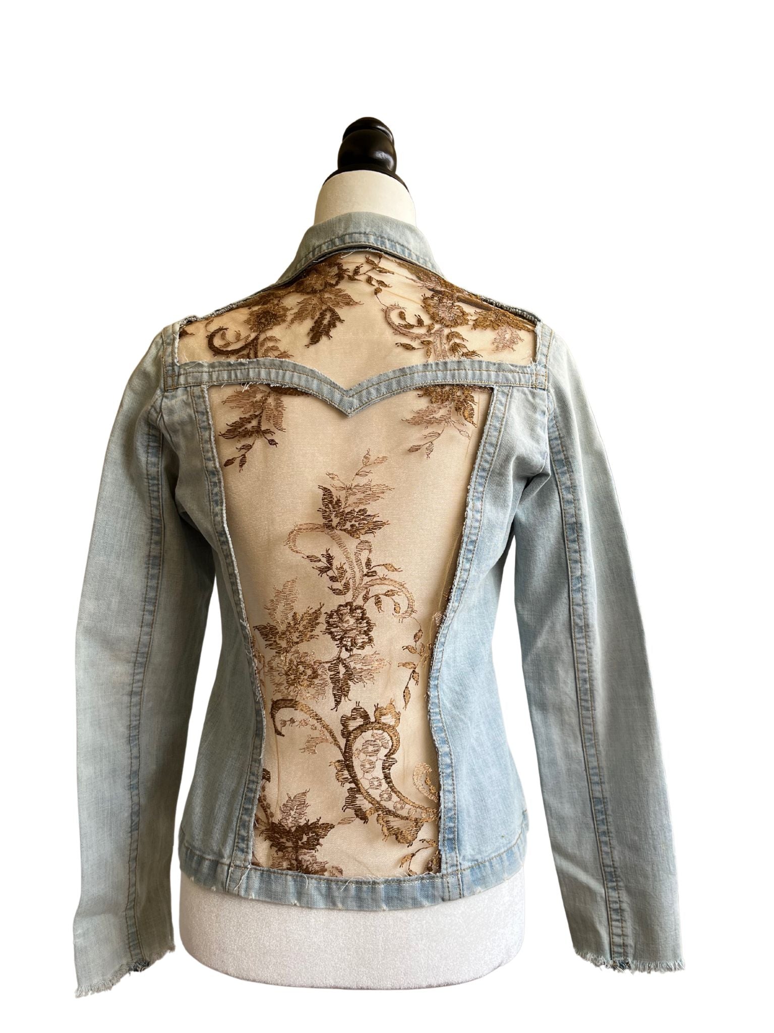 Chaqueta Bruma en denim claro, con flores bordadas sobre tul, tachuelas y encaje antiguo cosido a mano en la espalda.