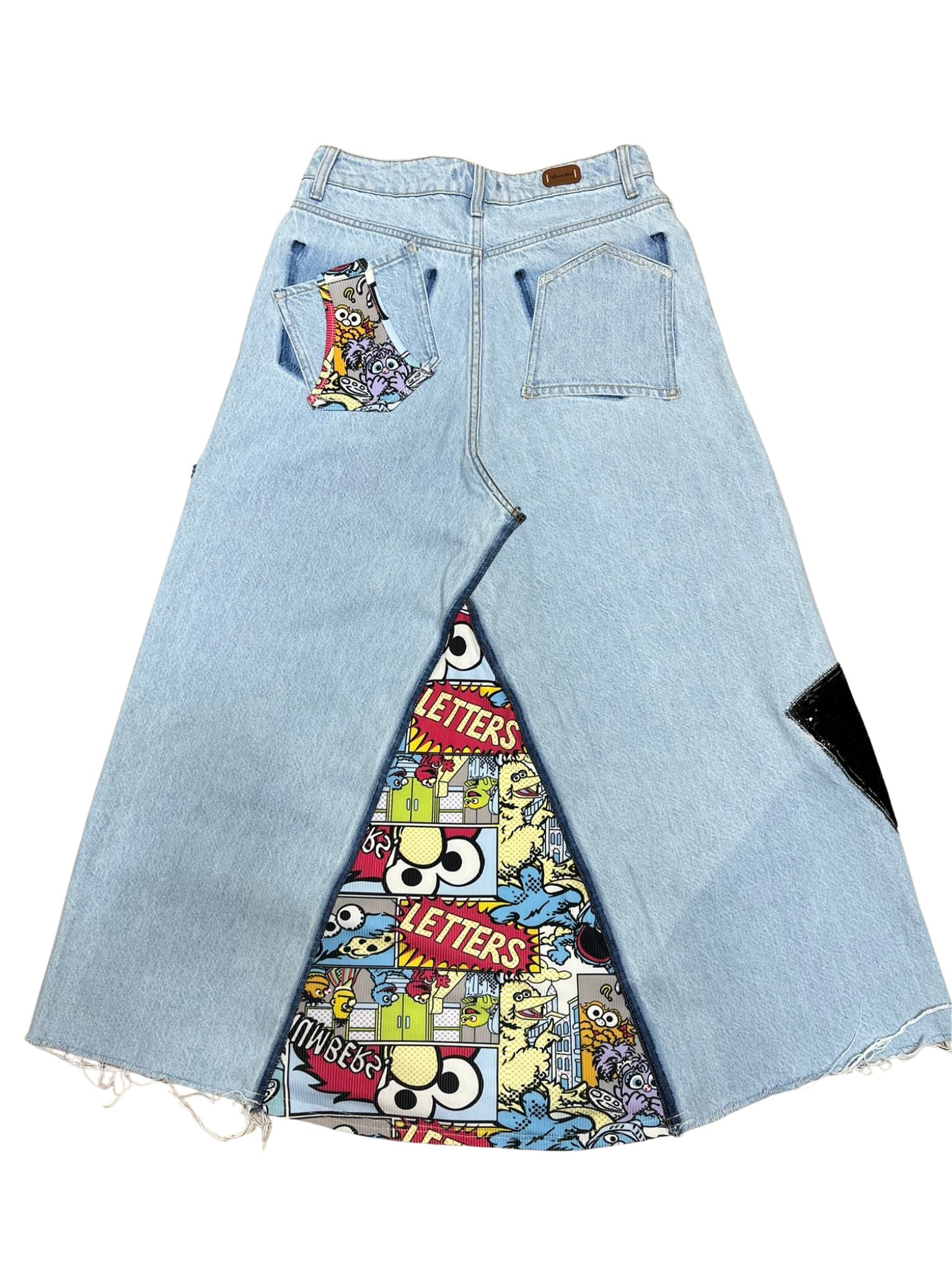 “Falda Hilena parte trasera de denim reciclado con pedrería, frase pintada a mano y parche de lentejuelas reversibles.”